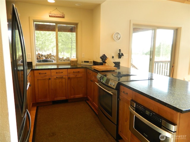 302 Summer Rd, Tonasket, WA 98855 - kitchen with appliances with stainless steel finishes, a peninsula, brown cabinetry, and dark stone countertops