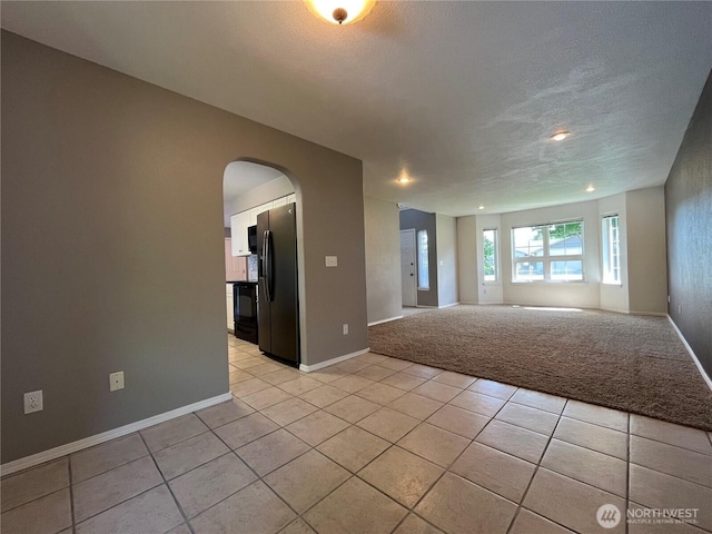 1516 4th St, Wenatchee, WA 98801 - empty room featuring arched walkways, baseboards, light tile patterned floors, a textured ceiling, and light carpet