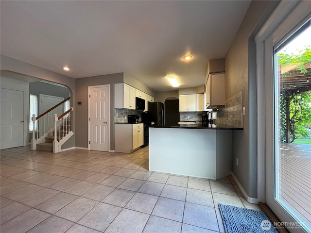 1516 4th St, Wenatchee, WA 98801 - kitchen with black microwave, decorative backsplash, dark countertops, light tile patterned floors, and arched walkways