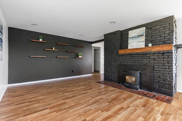13371 Eagle St, Anacortes, WA 98221 - unfurnished living room featuring baseboards, wood finished floors, a brick fireplace, and an accent wall