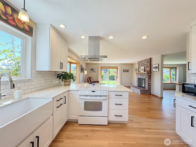 22 E Bedinger Rd, Sequim, WA 98382 - kitchen featuring white range with electric cooktop, a sink, a peninsula, wall chimney range hood, and healthy amount of natural light