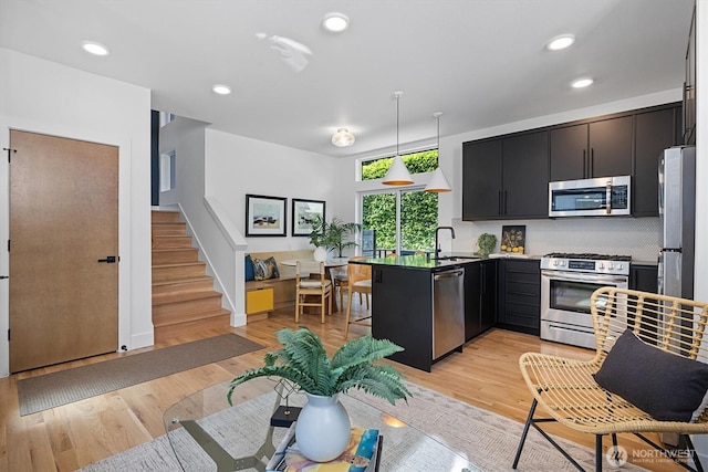 1134 32nd Ave E Unit B, Seattle, WA 98112 - kitchen with appliances with stainless steel finishes, a sink, a peninsula, dark cabinets, and pendant lighting