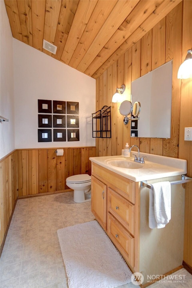 327 Cockle St SW, Ocean Shores, WA 98569 - bathroom featuring vaulted ceiling, wooden walls, vanity, a wainscoted wall, and toilet