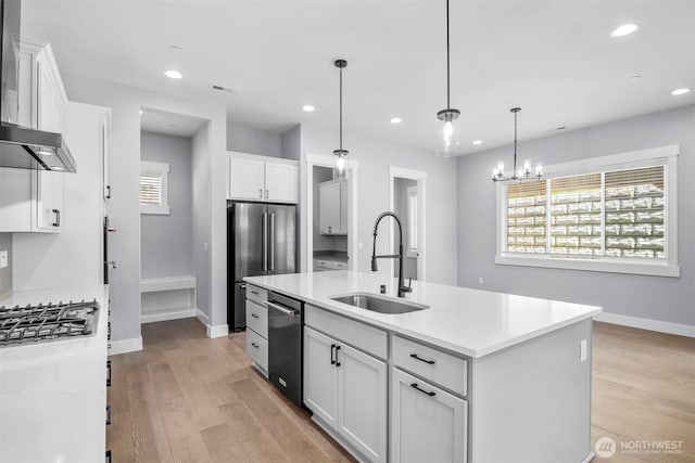 3829 95th Ave E, Edgewood, WA 98371 - kitchen featuring a sink, stainless steel appliances, white cabinetry, light countertops, and wall chimney range hood