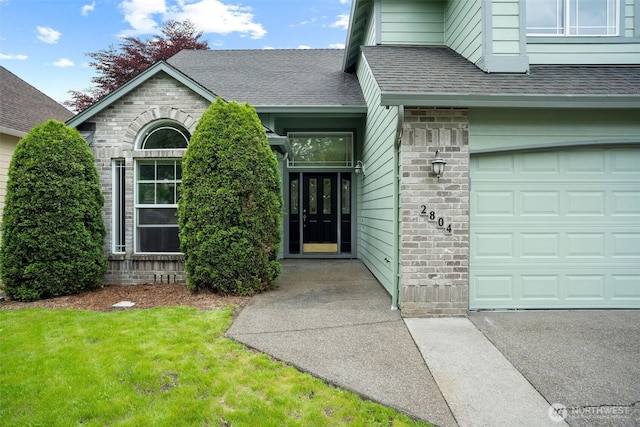 2804 177th, Vancouver, WA 98682 - view of exterior entry with a yard, roof with shingles, an attached garage, and brick siding