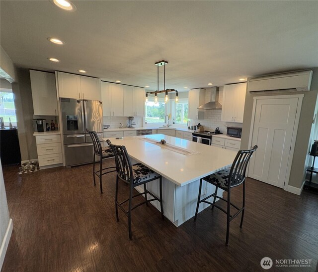 851 Heichel Rd, Camano Island, WA 98282 - kitchen featuring stainless steel appliances, wall chimney range hood, a wall mounted air conditioner, dark wood-type flooring, and recessed lighting