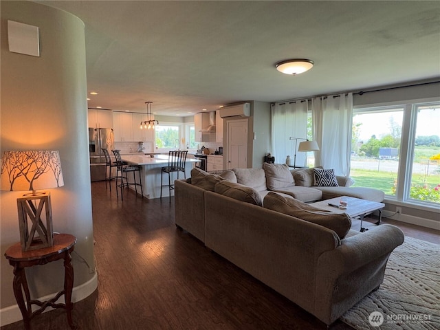 851 Heichel Rd, Camano Island, WA 98282 - living room featuring an AC wall unit, dark wood-style flooring, baseboards, and a chandelier
