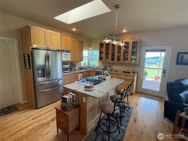 851 Heichel Rd, Camano Island, WA 98282 - kitchen featuring stainless steel fridge with ice dispenser, white microwave, a skylight, light wood-type flooring, and glass insert cabinets