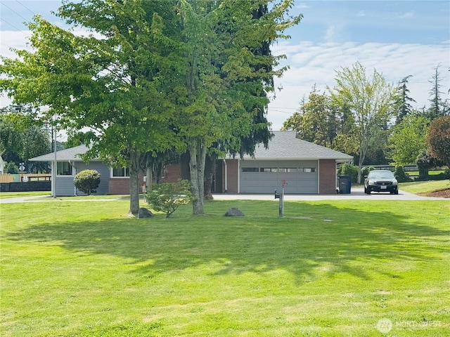 851 Heichel Rd, Camano Island, WA 98282 - view of property hidden behind natural elements featuring a front lawn, brick siding, a garage, and driveway