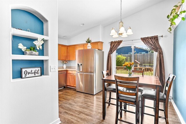 7382 Halibut Dr, Blaine, WA 98230 - dining space with vaulted ceiling, a chandelier, light wood-style floors, and baseboards