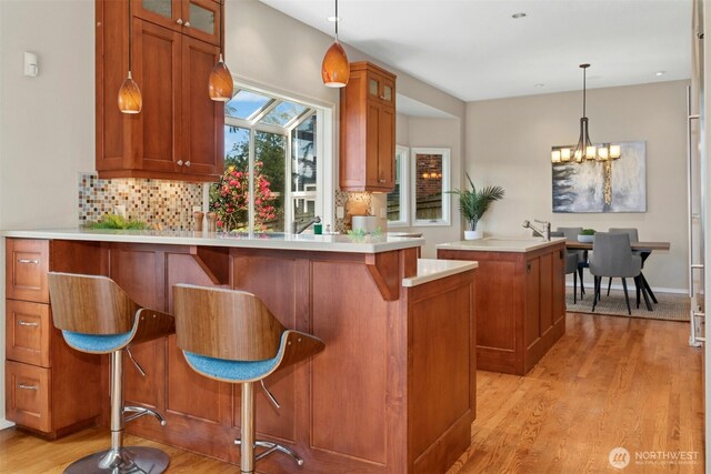 1805 179th Pl NE, Bellevue, WA 98008 - kitchen with brown cabinetry, glass insert cabinets, light wood-style floors, and decorative backsplash