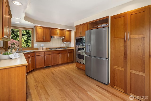 1211 6th Pl S, Edmonds, WA 98020 - kitchen with stainless steel appliances, brown cabinetry, light wood-style floors, under cabinet range hood, and recessed lighting