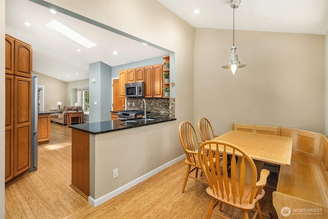 23018 NE 25th Way, Sammamish, WA 98074 - kitchen featuring stainless steel appliances, light wood finished floors, backsplash, a skylight, and vaulted ceiling