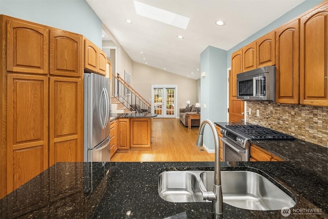 23018 NE 25th Way, Sammamish, WA 98074 - kitchen featuring stainless steel appliances, a sink, a skylight, vaulted ceiling, and dark stone countertops