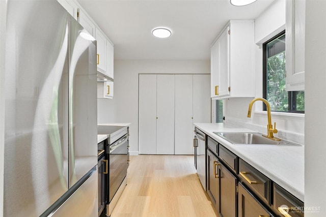 5410 240th St SW, Mountlake Terrace, WA 98043 - kitchen with stainless steel appliances, light wood-style floors, light countertops, white cabinets, and under cabinet range hood