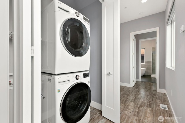 10445 Dixon Dr S, Seattle, WA 98178 - laundry area with stacked washing machine and dryer, baseboards, and wood finished floors
