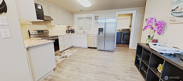 3060 NE Wheeler St, Poulsbo, WA 98370 - kitchen featuring appliances with stainless steel finishes, washer and dryer, white cabinets, under cabinet range hood, and light wood finished floors