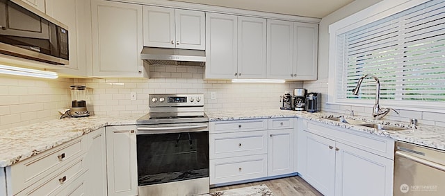 3060 NE Wheeler St, Poulsbo, WA 98370 - kitchen featuring appliances with stainless steel finishes, under cabinet range hood, a sink, decorative backsplash, and light stone counters
