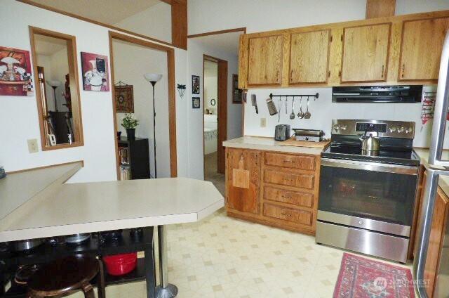 716 Dennis St SE Unit 48, Tumwater, WA 98501 - kitchen featuring electric range, range hood, light countertops, light floors, and brown cabinetry