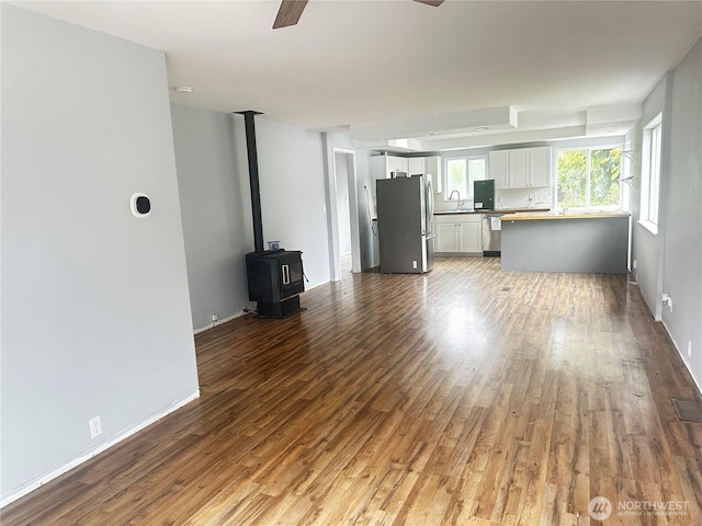 620 Hull Ave, Port Orchard, WA 98366 - unfurnished living room with a sink, wood finished floors, ceiling fan, a wood stove, and baseboards