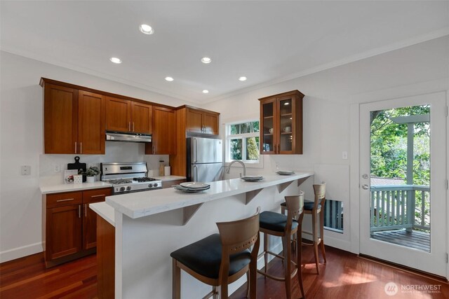1126 24th Ave, Seattle, WA 98122 - kitchen featuring gas stove, freestanding refrigerator, under cabinet range hood, glass insert cabinets, and a kitchen bar