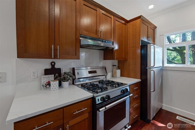 1126 24th Ave, Seattle, WA 98122 - kitchen featuring stainless steel range with gas cooktop, freestanding refrigerator, under cabinet range hood, brown cabinetry, and baseboards