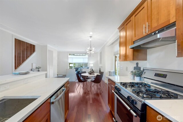 1126 24th Ave, Seattle, WA 98122 - kitchen with stainless steel appliances, under cabinet range hood, crown molding, dark wood-style floors, and brown cabinets