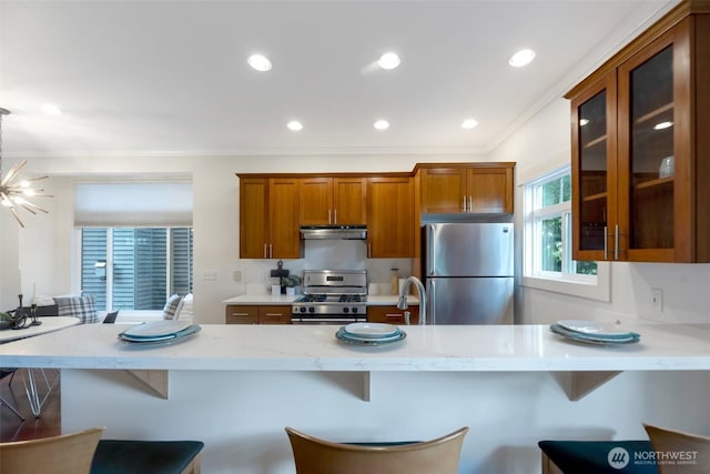 1126 24th Ave, Seattle, WA 98122 - kitchen featuring appliances with stainless steel finishes, under cabinet range hood, glass insert cabinets, brown cabinets, and recessed lighting