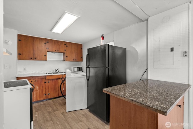 4222 S Spencer St, Seattle, WA 98118 - kitchen featuring washer / dryer, freestanding refrigerator, range, light wood finished floors, and brown cabinets