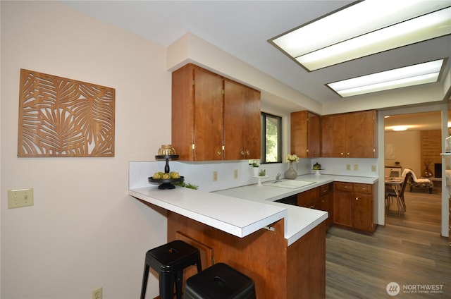 18215 108th Ave NE, Bothell, WA 98011 - kitchen featuring brown cabinetry, a peninsula, light countertops, dark wood-style floors, and a kitchen bar
