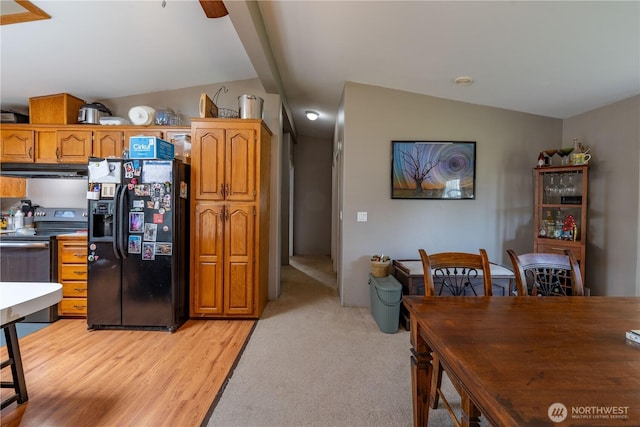 1822 W Devanny Ln, Port Angeles, WA 98363 - kitchen with black refrigerator with ice dispenser, stainless steel range with electric cooktop, lofted ceiling, under cabinet range hood, and brown cabinetry
