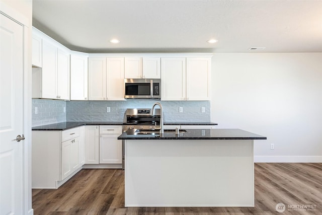 4214 W Sandy Ct, Moses Lake, WA 98837 - kitchen featuring appliances with stainless steel finishes, a sink, a kitchen island with sink, dark stone countertops, and wood finished floors