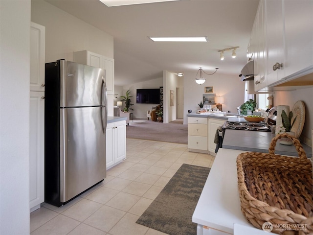 7127 Ortelius Dr, Ilwaco, WA 98624 - kitchen featuring freestanding refrigerator, light tile patterned floors, vaulted ceiling, a peninsula, and light carpet
