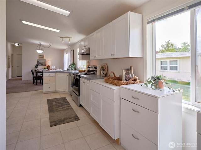 7127 Ortelius Dr, Ilwaco, WA 98624 - kitchen with stainless steel electric stove, a peninsula, light tile patterned flooring, white cabinetry, and under cabinet range hood