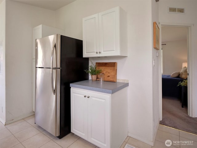 7127 Ortelius Dr, Ilwaco, WA 98624 - kitchen featuring freestanding refrigerator, white cabinets, light tile patterned floors, and baseboards