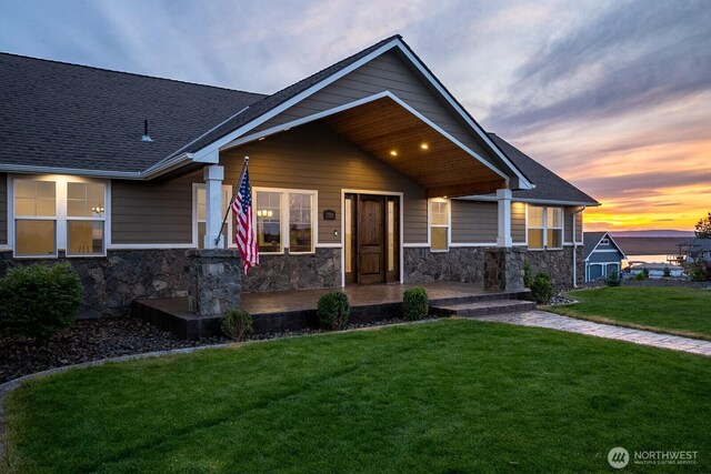 7328 Stonecrest Rd NE, Moses Lake, WA 98837 - view of front of property with stone siding, covered porch, a lawn, and roof with shingles
