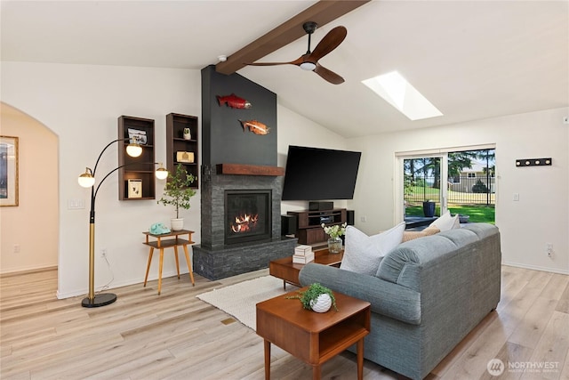 1361 E Old Ranch Rd, Allyn, WA 98524 - living room with light wood finished floors, a skylight, a glass covered fireplace, ceiling fan, and arched walkways