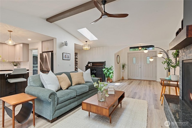 1361 E Old Ranch Rd, Allyn, WA 98524 - living area featuring a skylight, a ceiling fan, light wood-type flooring, and a warm lit fireplace