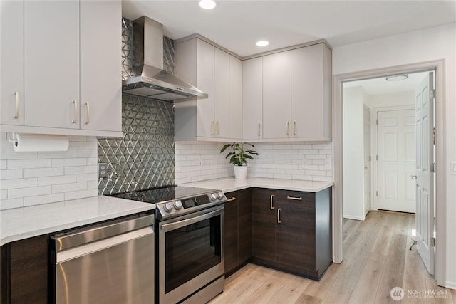 1361 E Old Ranch Rd, Allyn, WA 98524 - kitchen with wall chimney range hood, appliances with stainless steel finishes, light wood-style flooring, dark brown cabinetry, and recessed lighting