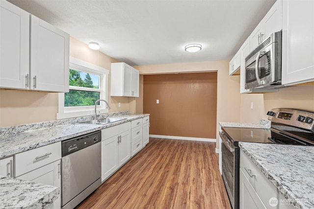 2914 Columbia Heights Rd, Longview, WA 98632 - kitchen with appliances with stainless steel finishes, a sink, light wood-style flooring, white cabinetry, and baseboards