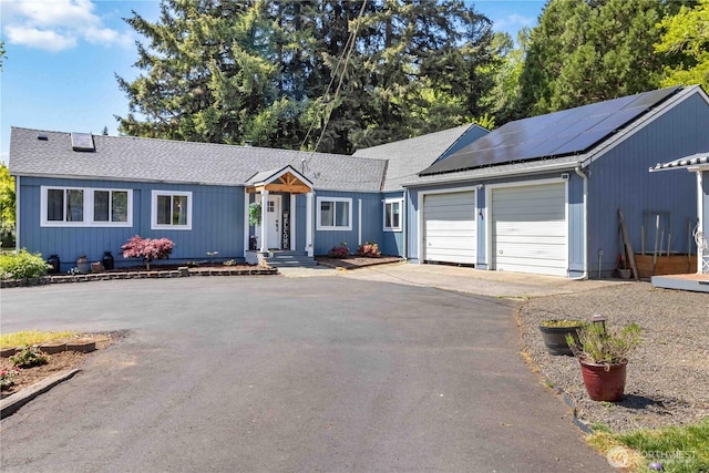 2337 W Castleman St, Longview, WA 98632 - ranch-style house featuring a garage, driveway, roof mounted solar panels, and roof with shingles