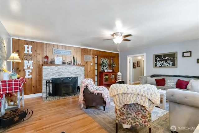 2337 W Castleman St, Longview, WA 98632 - living area featuring wood finished floors, a ceiling fan, wood walls, a stone fireplace, and baseboards