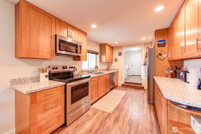 4718 252nd St NE, Arlington, WA 98223 - kitchen featuring appliances with stainless steel finishes, light wood-type flooring, a sink, recessed lighting, and light stone counters
