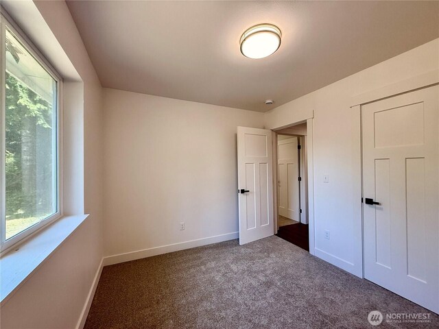 127 Olympic View Ave NE, Ocean Shores, WA 98569 - unfurnished bedroom featuring multiple windows and dark colored carpet