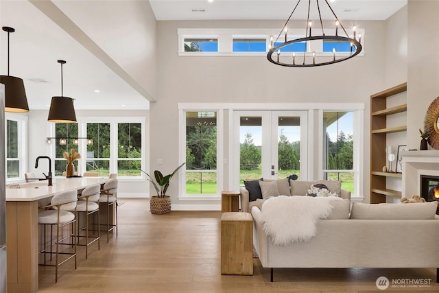 5712 Denali Ln, Bellingham, WA 98226 - living area featuring a towering ceiling, a chandelier, light wood finished floors, french doors, and a glass covered fireplace