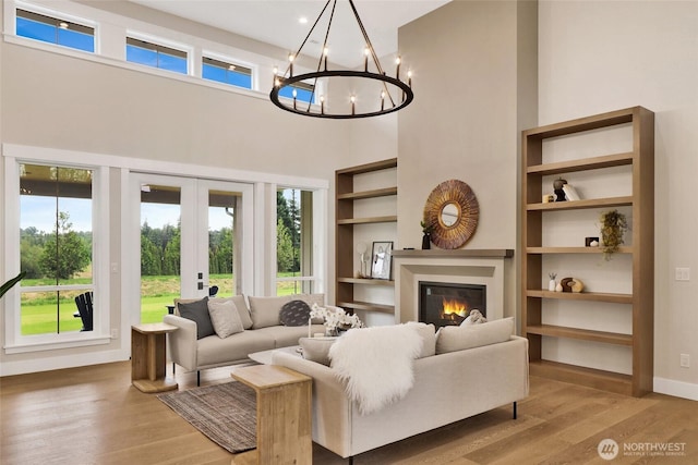 5712 Denali Ln, Bellingham, WA 98226 - living area featuring wood finished floors, french doors, a glass covered fireplace, a chandelier, and a high ceiling
