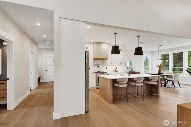 5712 Denali Ln, Bellingham, WA 98226 - kitchen with appliances with stainless steel finishes, light wood-style flooring, white cabinets, an island with sink, and a breakfast bar