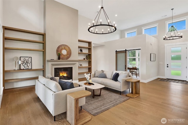 5712 Denali Ln, Bellingham, WA 98226 - living room featuring a chandelier, a towering ceiling, wood finished floors, a glass covered fireplace, and recessed lighting