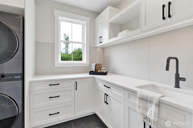 5712 Denali Ln, Bellingham, WA 98226 - washroom featuring stacked washer and clothes dryer, cabinet space, and tile walls