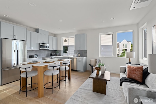 4519A Bagley Ave N, Seattle, WA 98103 - kitchen featuring appliances with stainless steel finishes, open floor plan, a breakfast bar area, light wood-type flooring, and backsplash